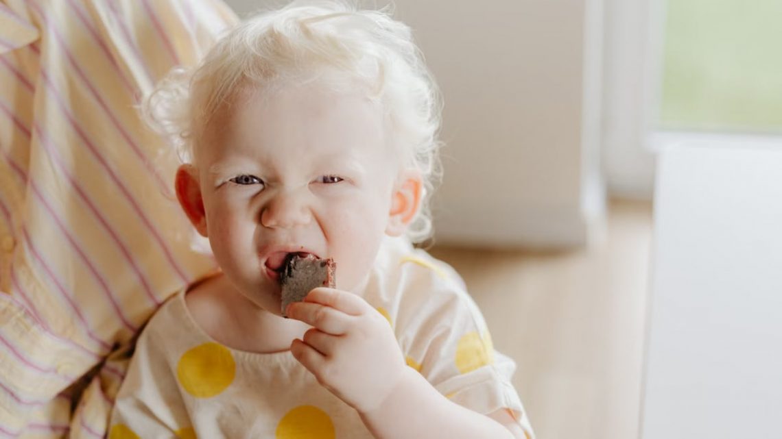 A cute albino child enjoying a chocolate snack indoors. Warm and playful vibe.
