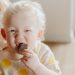 A cute albino child enjoying a chocolate snack indoors. Warm and playful vibe.