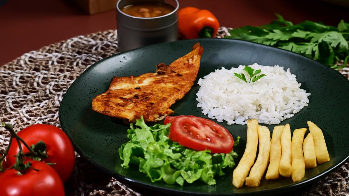 A vibrant plate featuring grilled chicken breast, white rice, fries, and fresh vegetables.